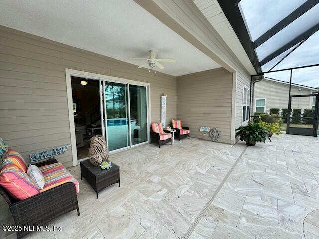 view of patio featuring ceiling fan and glass enclosure