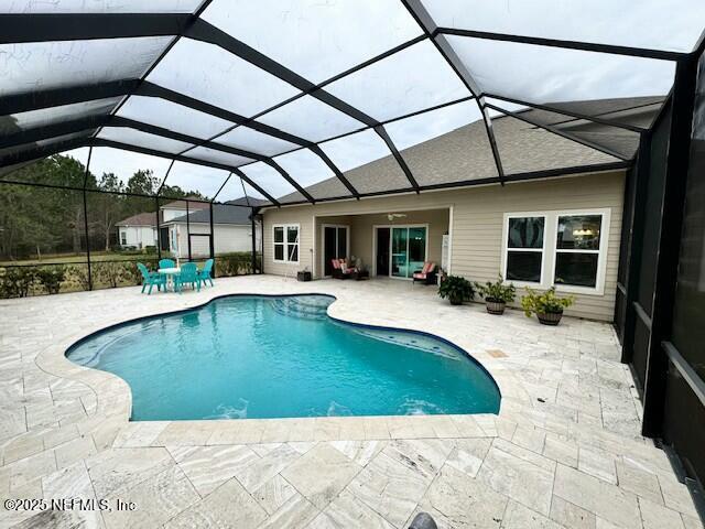 view of pool with glass enclosure and a patio