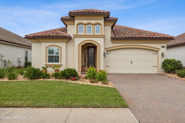 mediterranean / spanish house featuring a garage and a front lawn