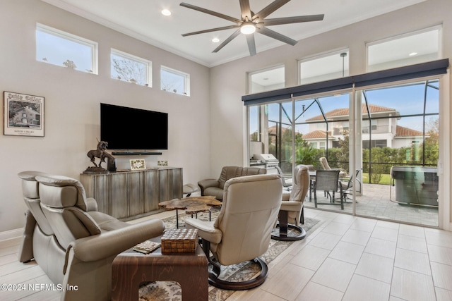 living room with a towering ceiling, ceiling fan, crown molding, and light tile patterned floors