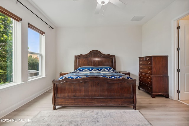 bedroom featuring ceiling fan, multiple windows, and light hardwood / wood-style flooring