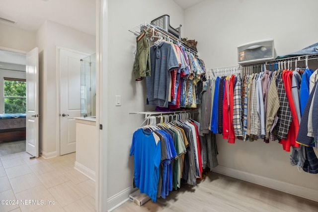 walk in closet with light hardwood / wood-style flooring