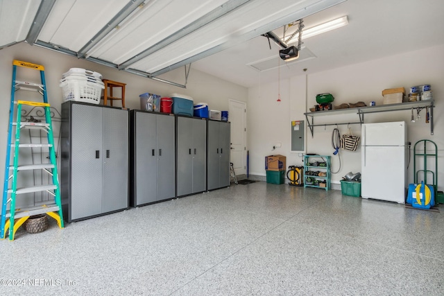 garage with electric panel, white refrigerator, and a garage door opener