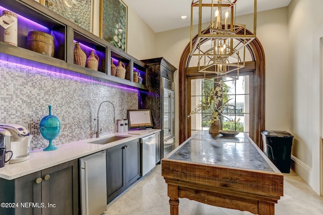 kitchen featuring tasteful backsplash, stainless steel appliances, hanging light fixtures, sink, and a chandelier