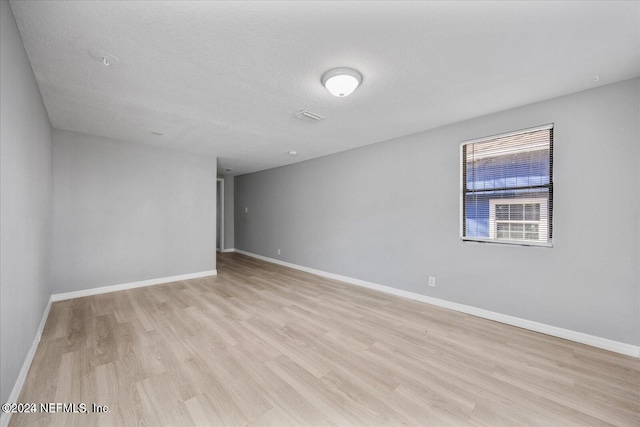 empty room with light hardwood / wood-style floors and a textured ceiling