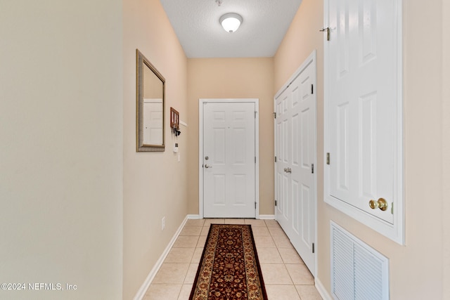 doorway featuring a textured ceiling and light tile patterned floors