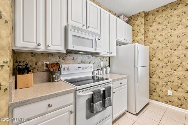 7801 Point Meadows Dr Unit 8406, Jacksonville, FL 32256 - kitchen with wallpapered walls, baseboards, light tile patterned floors, white appliances, and white cabinetry