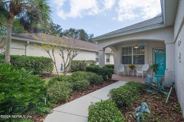 193 Lions Gate Dr, Saint Augustine, FL 32080 - property entrance with a ceiling fan, stucco siding, a porch, and roof with shingles
