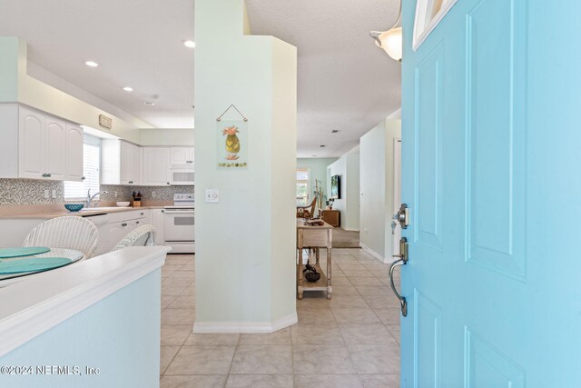 193 Lions Gate Dr, Saint Augustine, FL 32080 - kitchen with white appliances, white cabinets, light tile patterned floors, backsplash, and a sink