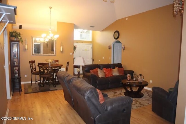 living room with light wood-style flooring, baseboards, vaulted ceiling, and a notable chandelier