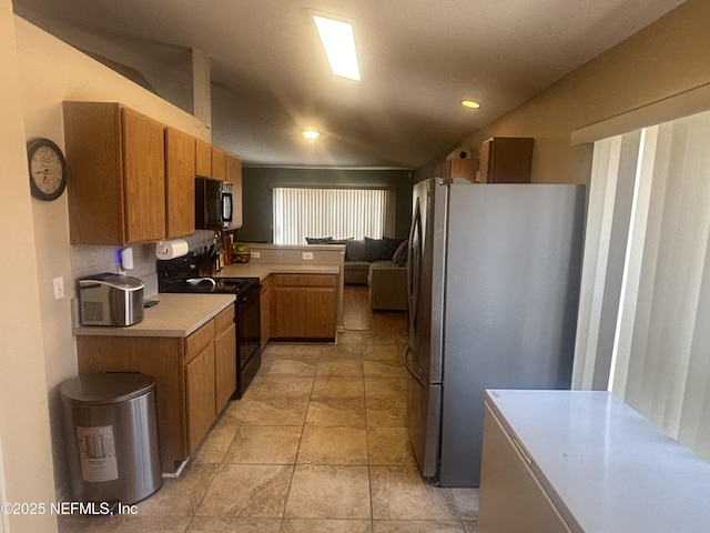 694 Cherry Bark Dr N, Jacksonville, FL 32218 - kitchen with brown cabinets, light countertops, freestanding refrigerator, a peninsula, and black range with electric stovetop