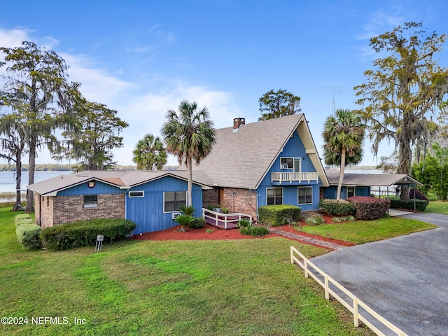 view of front of house featuring a water view, a front lawn, and a balcony