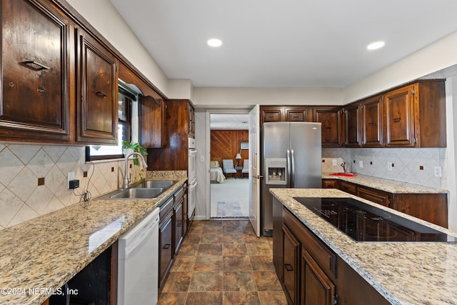 kitchen featuring black electric cooktop, dishwasher, sink, backsplash, and stainless steel fridge