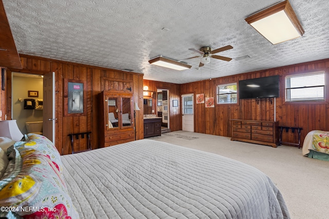 bedroom featuring electric panel, a textured ceiling, carpet flooring, and ensuite bath