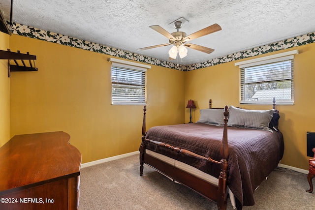 carpeted bedroom with ceiling fan, multiple windows, and a textured ceiling