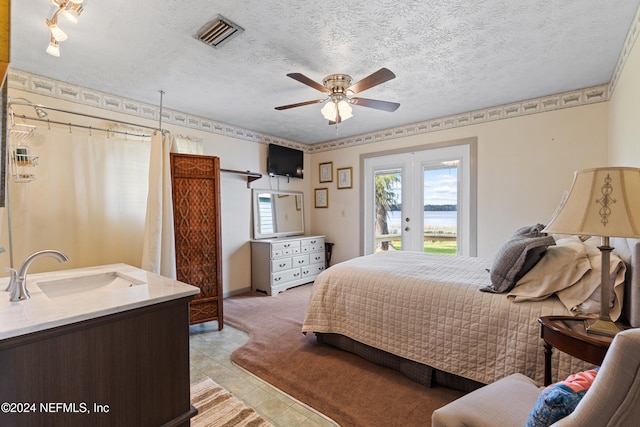 tiled bedroom with french doors, a textured ceiling, access to exterior, sink, and ceiling fan