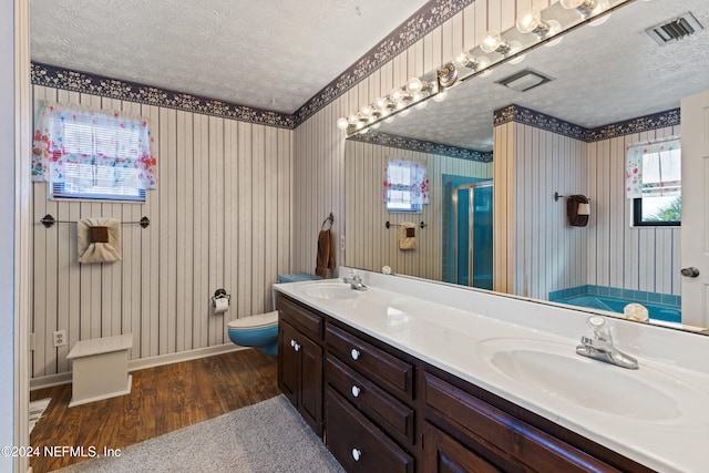 bathroom featuring vanity, hardwood / wood-style flooring, a textured ceiling, and walk in shower