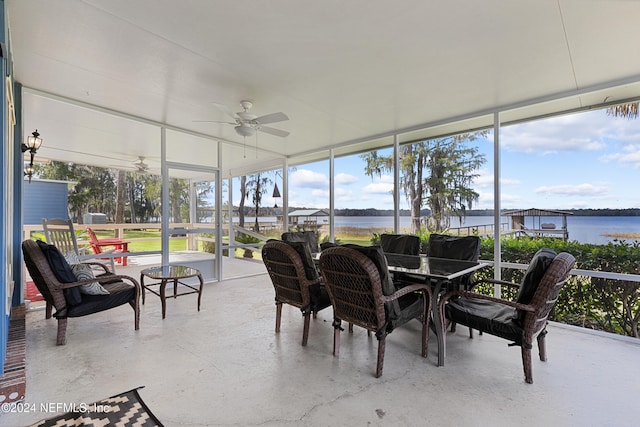 sunroom with ceiling fan and a water view