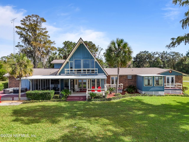 rear view of house featuring a lawn and a sunroom