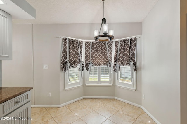 unfurnished dining area with an inviting chandelier, a textured ceiling, and a healthy amount of sunlight