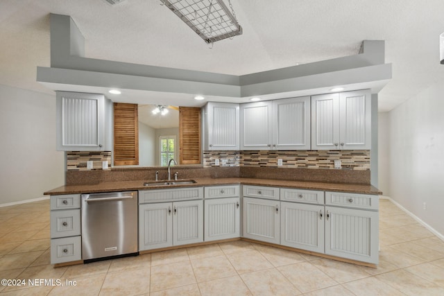 kitchen featuring light tile patterned flooring, kitchen peninsula, stainless steel dishwasher, and sink