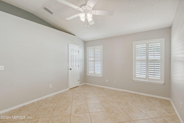 tiled empty room featuring ceiling fan, a healthy amount of sunlight, a textured ceiling, and vaulted ceiling