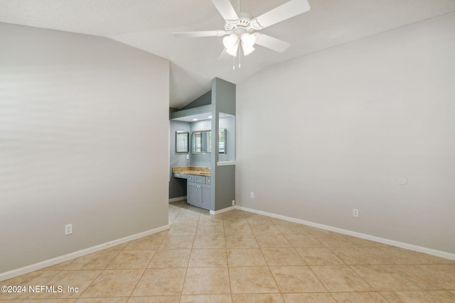 empty room featuring lofted ceiling, light tile patterned flooring, and ceiling fan