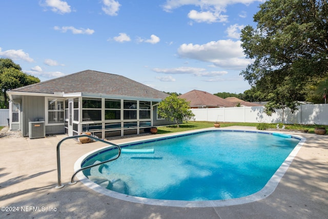 view of swimming pool with a patio area, central AC unit, and a sunroom