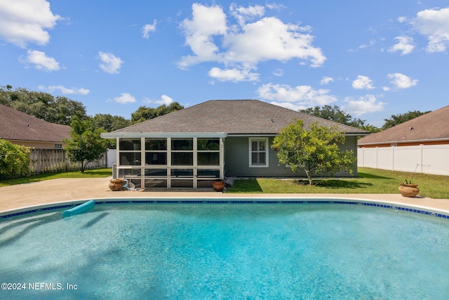 view of pool with a patio, a sunroom, and a lawn