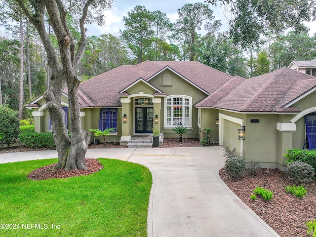 view of front of house with french doors, a front lawn, and a garage