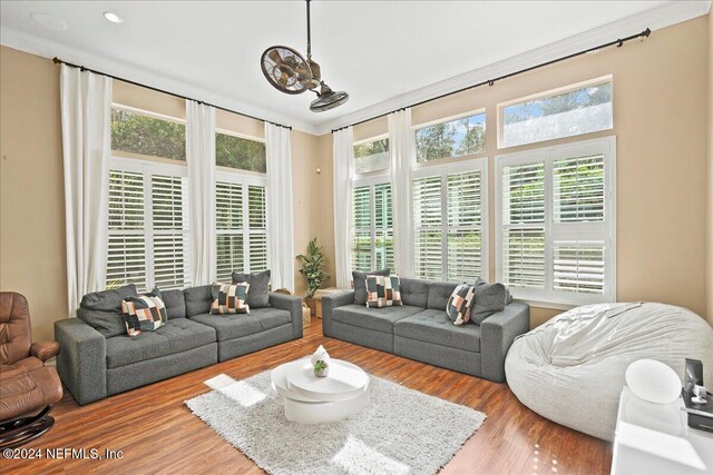 living room with plenty of natural light, light wood-type flooring, and ornamental molding