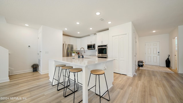 kitchen featuring appliances with stainless steel finishes, sink, an island with sink, light hardwood / wood-style floors, and a breakfast bar area