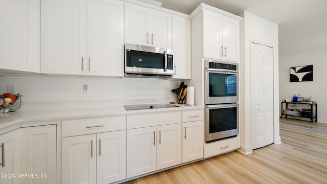 kitchen with white cabinets, light hardwood / wood-style floors, and appliances with stainless steel finishes