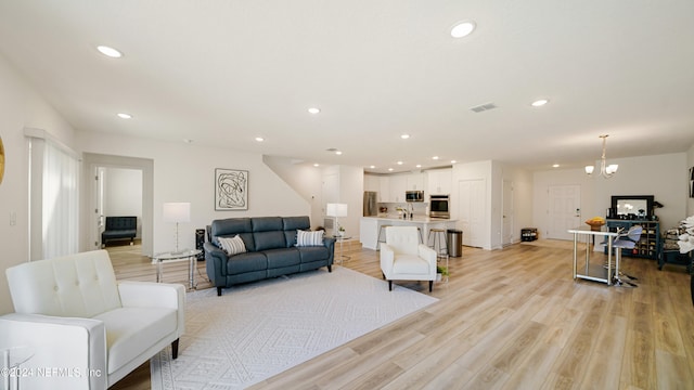 living room with light hardwood / wood-style floors and an inviting chandelier