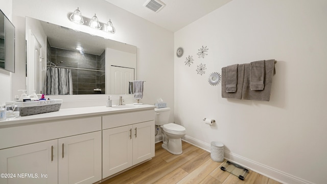 bathroom with walk in shower, vanity, toilet, and hardwood / wood-style floors