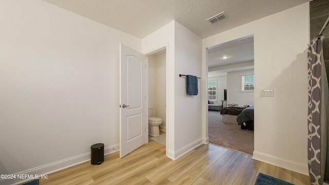 hallway with a textured ceiling and light wood-type flooring