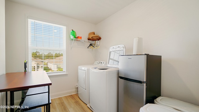 laundry area with light hardwood / wood-style floors, independent washer and dryer, and a healthy amount of sunlight