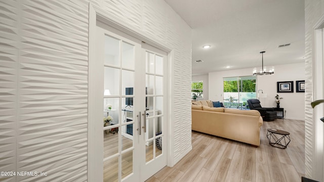 living room featuring french doors, light wood-type flooring, and a chandelier