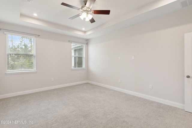 carpeted empty room with a raised ceiling and ceiling fan