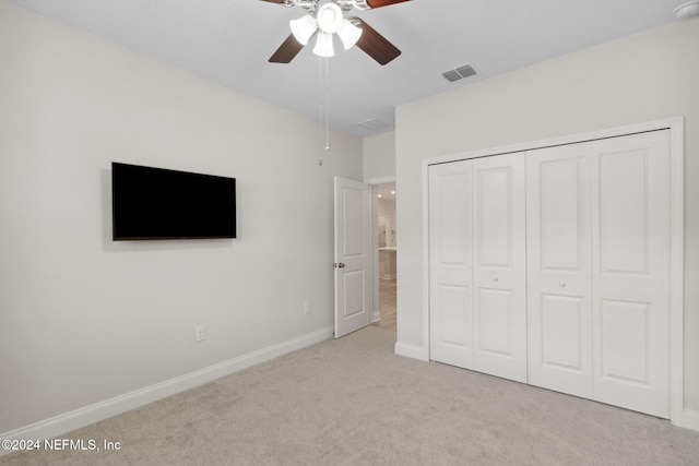 unfurnished bedroom with ceiling fan, light carpet, and a closet