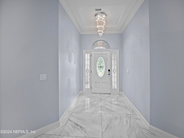 foyer entrance featuring ornamental molding, a notable chandelier, and a raised ceiling