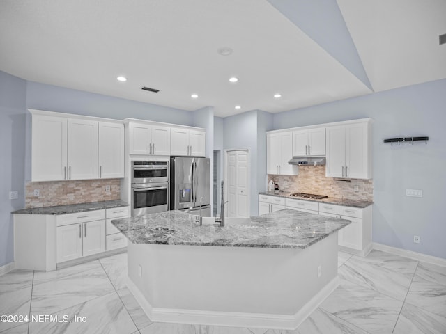 kitchen featuring sink, stainless steel appliances, white cabinets, decorative backsplash, and a center island with sink