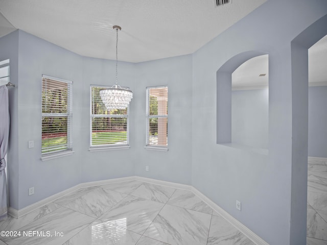 unfurnished room featuring a textured ceiling and a chandelier