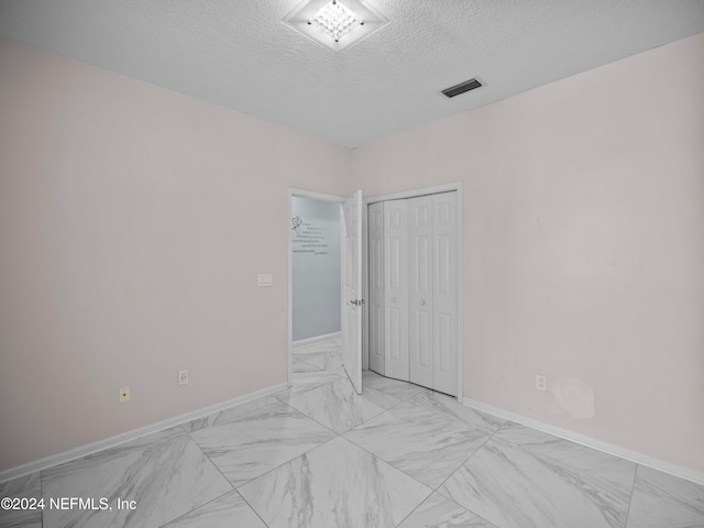 unfurnished room featuring a textured ceiling