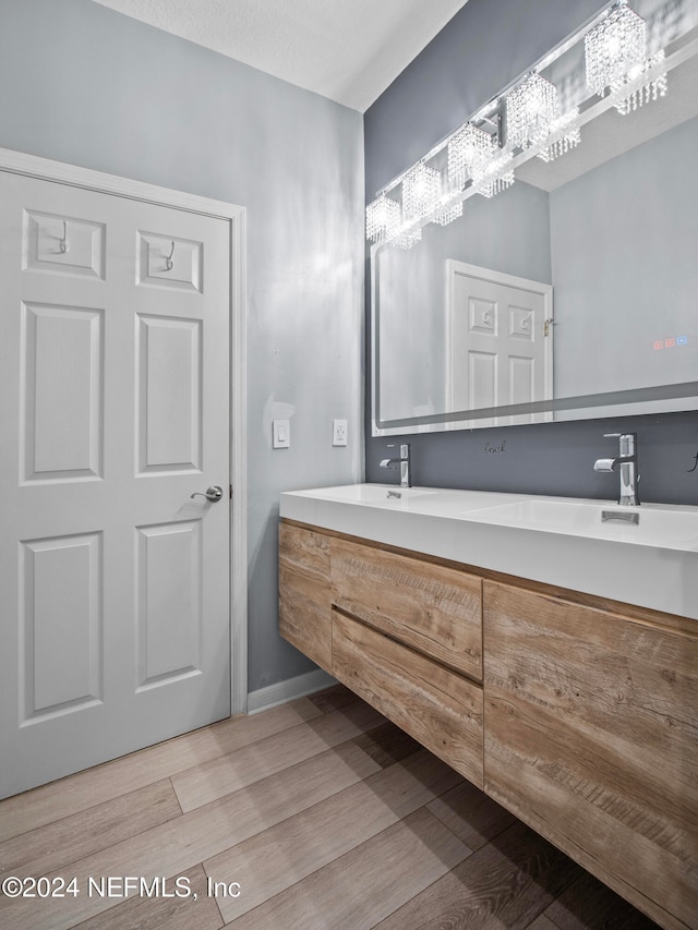 bathroom with vanity, an inviting chandelier, and hardwood / wood-style floors