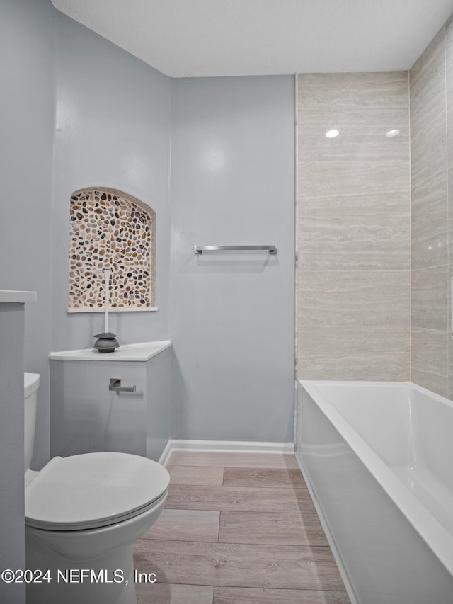 bathroom with a bath, toilet, and hardwood / wood-style floors