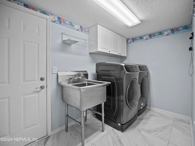 laundry room with cabinets, a textured ceiling, and washing machine and dryer