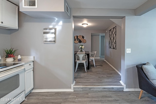 kitchen with white cabinetry, light wood-type flooring, and electric stove