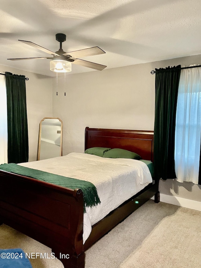 bedroom with a textured ceiling, carpet floors, and ceiling fan