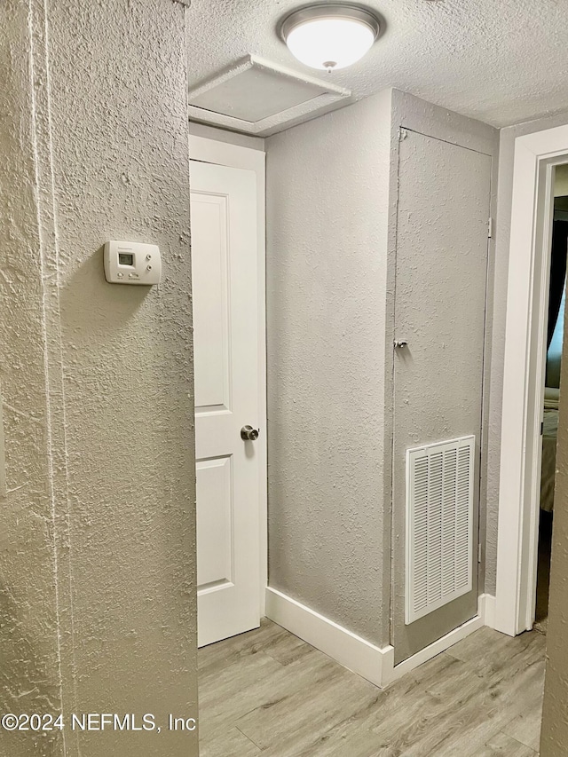 hallway featuring wood-type flooring and a textured ceiling